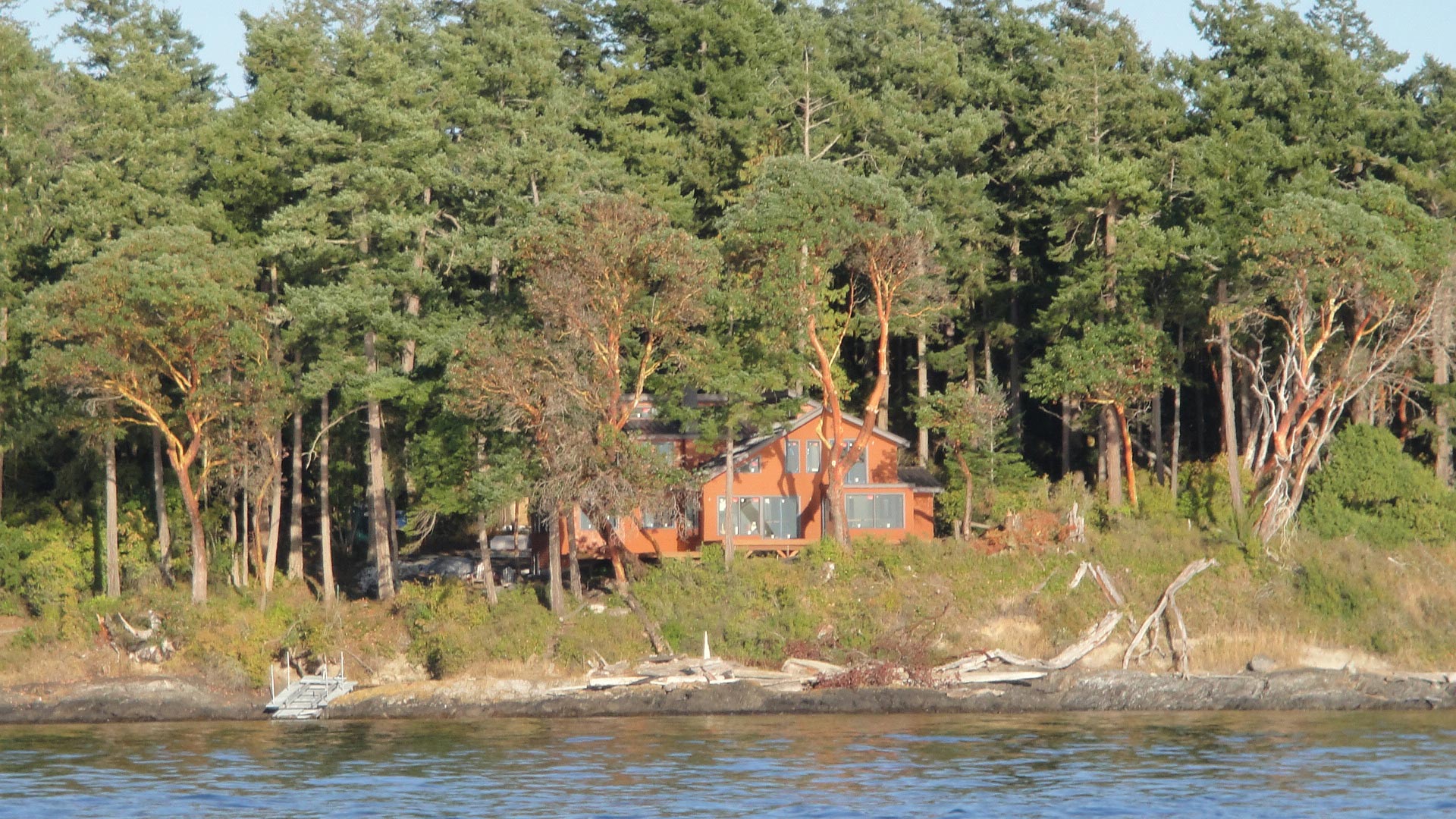 Completed custom home in front of a lake, surrounded by trees.